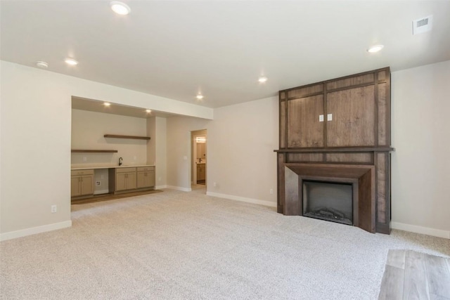 unfurnished living room featuring sink and light colored carpet