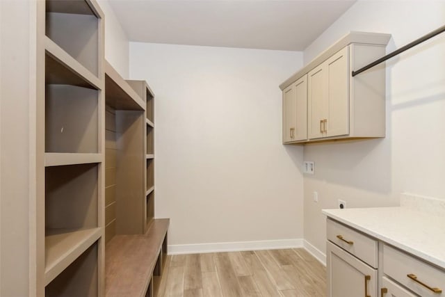 clothes washing area with electric dryer hookup, cabinets, light hardwood / wood-style floors, and washer hookup