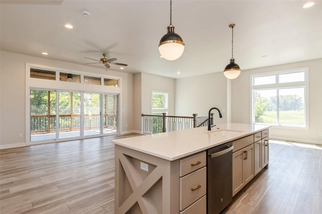 kitchen featuring a kitchen island with sink, hanging light fixtures, a wealth of natural light, sink, and stainless steel dishwasher