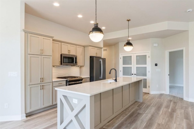 kitchen with stainless steel appliances, an island with sink, pendant lighting, and sink