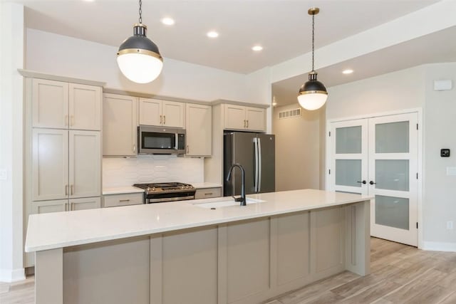 kitchen featuring sink, hanging light fixtures, an island with sink, and appliances with stainless steel finishes