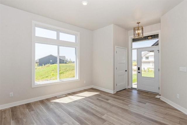 entrance foyer featuring light hardwood / wood-style floors, a wealth of natural light, and a notable chandelier