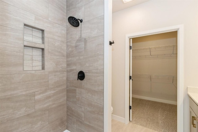 bathroom with a tile shower and vanity