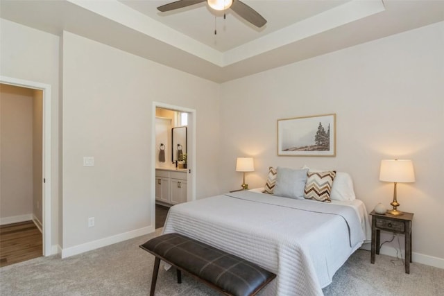 carpeted bedroom featuring ceiling fan, connected bathroom, and a tray ceiling