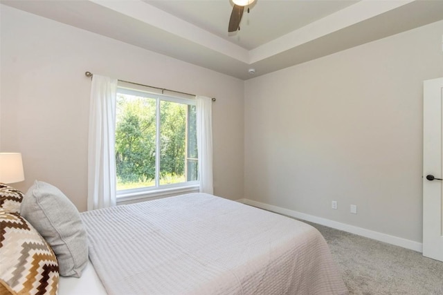 bedroom with carpet floors, ceiling fan, and a tray ceiling