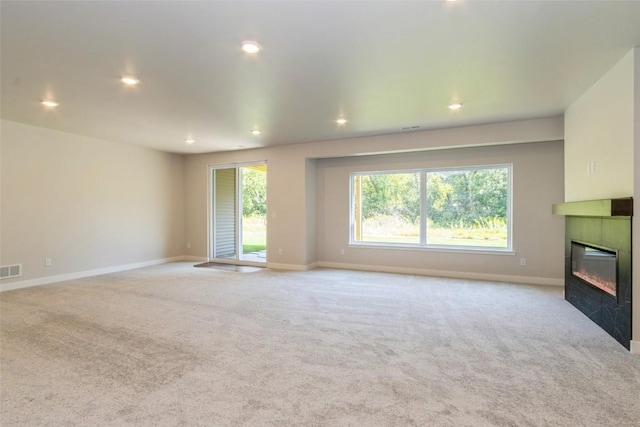 unfurnished living room with a tiled fireplace and light carpet