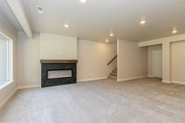 unfurnished living room featuring a premium fireplace and light carpet