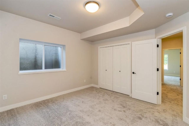 unfurnished bedroom featuring a closet and light carpet