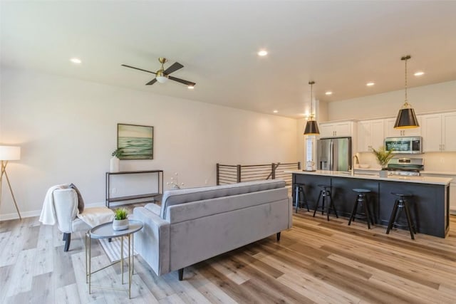 living room featuring ceiling fan, light hardwood / wood-style flooring, and sink