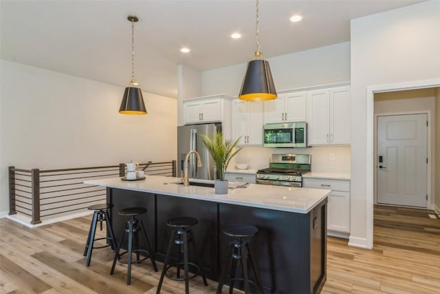 kitchen with white cabinets, a kitchen breakfast bar, a kitchen island with sink, and appliances with stainless steel finishes