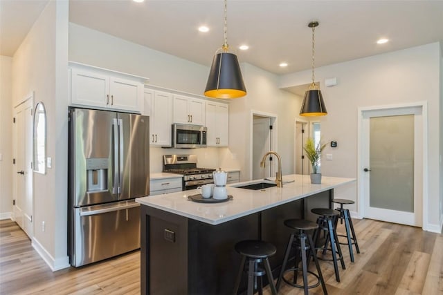 kitchen with decorative light fixtures, white cabinetry, a kitchen island with sink, and appliances with stainless steel finishes