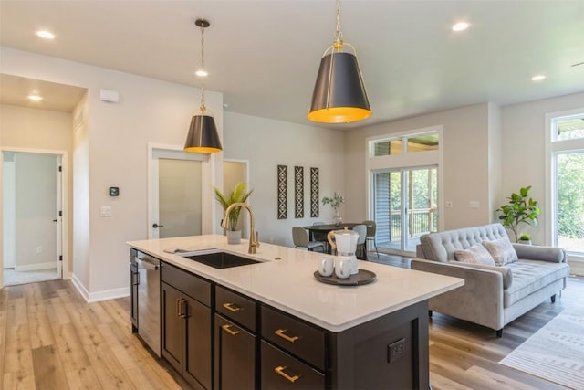 kitchen with decorative light fixtures, an island with sink, stainless steel dishwasher, and sink