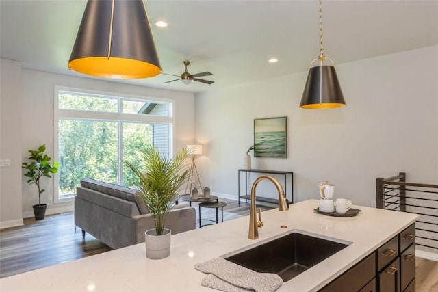 kitchen featuring sink, decorative light fixtures, ceiling fan, light stone countertops, and dark hardwood / wood-style flooring