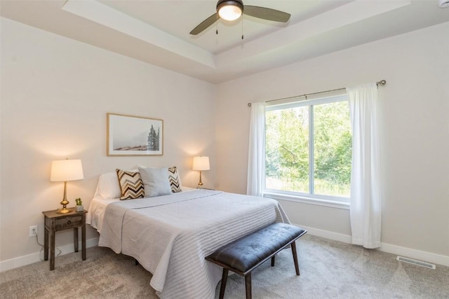 carpeted bedroom featuring ceiling fan and a tray ceiling