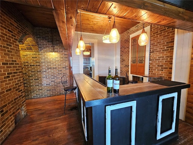 bar featuring dark hardwood / wood-style floors, hanging light fixtures, brick wall, wooden counters, and beverage cooler