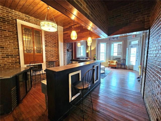 kitchen with dark wood-type flooring, pendant lighting, brick wall, a breakfast bar, and cooling unit