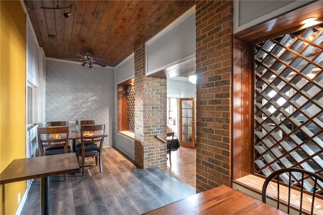 dining space with wood ceiling, wood walls, brick wall, ceiling fan, and dark hardwood / wood-style flooring