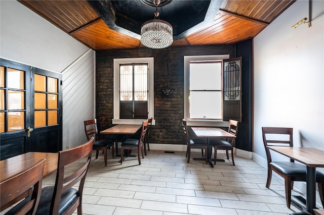 dining room featuring wood walls, a notable chandelier, and wood ceiling