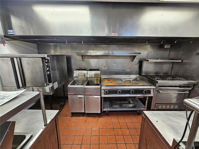 kitchen featuring refrigerator, dark tile patterned floors, and stainless steel gas stove