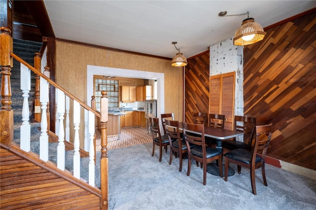 dining space featuring ornamental molding, carpet floors, and wooden walls