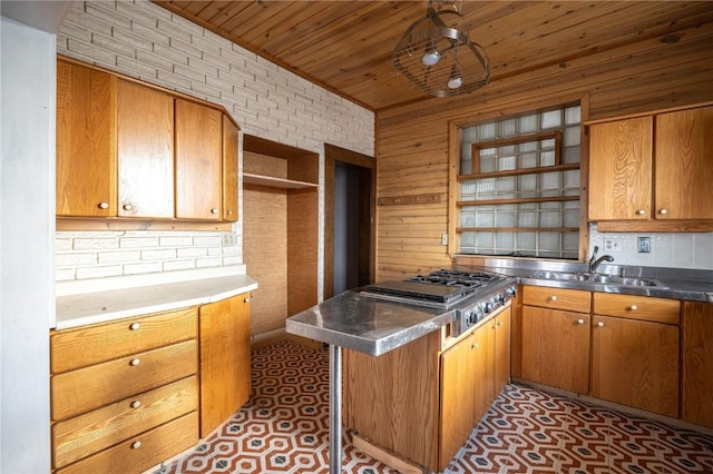 kitchen featuring sink, brick wall, wood ceiling, and stainless steel counters