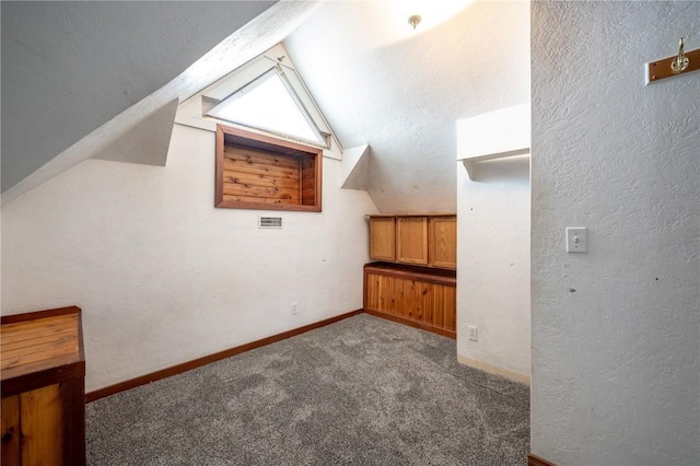 additional living space featuring lofted ceiling and dark colored carpet