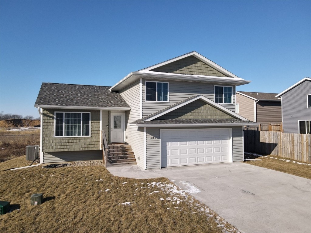 tri-level home with central air condition unit and a garage