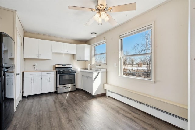 kitchen with black fridge, white cabinetry, stainless steel gas stove, and a baseboard heating unit