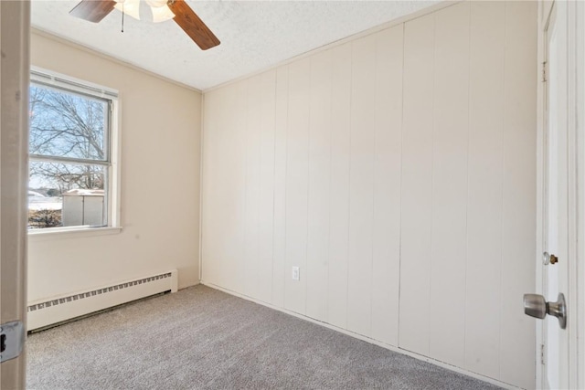 unfurnished room featuring a textured ceiling, wood walls, a baseboard heating unit, ceiling fan, and light carpet