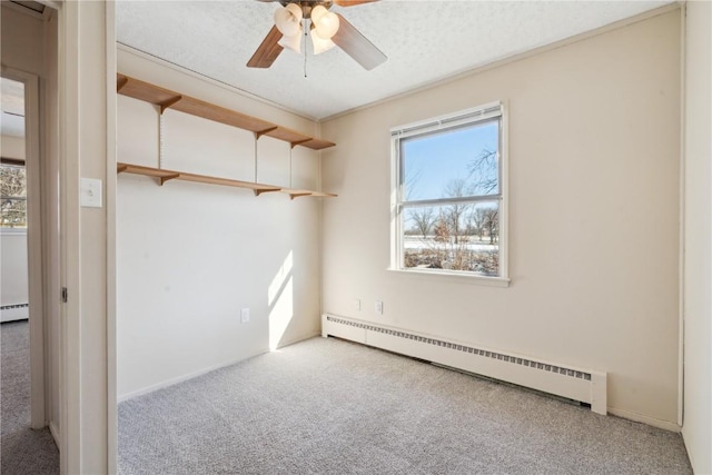 carpeted empty room featuring a textured ceiling, ceiling fan, and a baseboard radiator