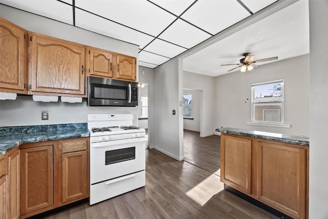 kitchen featuring dark hardwood / wood-style flooring, white gas range oven, and ceiling fan