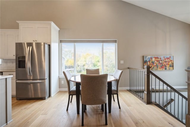 dining area with light hardwood / wood-style floors and vaulted ceiling