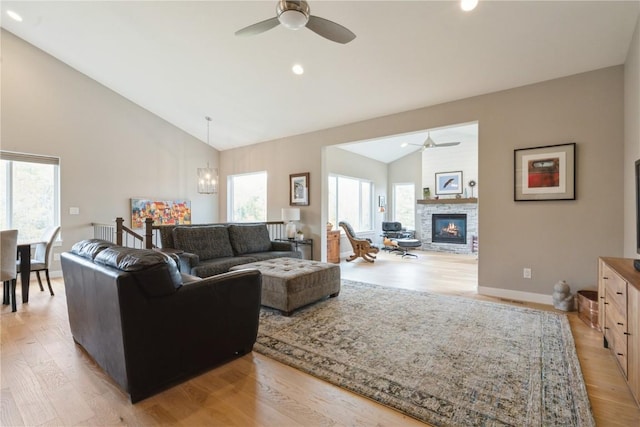 living room with vaulted ceiling, a fireplace, plenty of natural light, and light hardwood / wood-style flooring