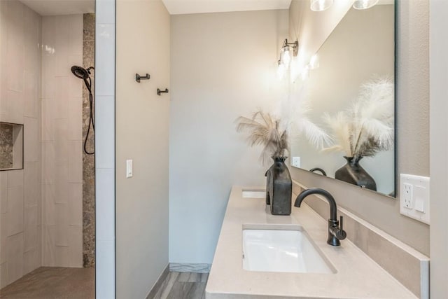 bathroom featuring a tile shower, hardwood / wood-style flooring, and vanity