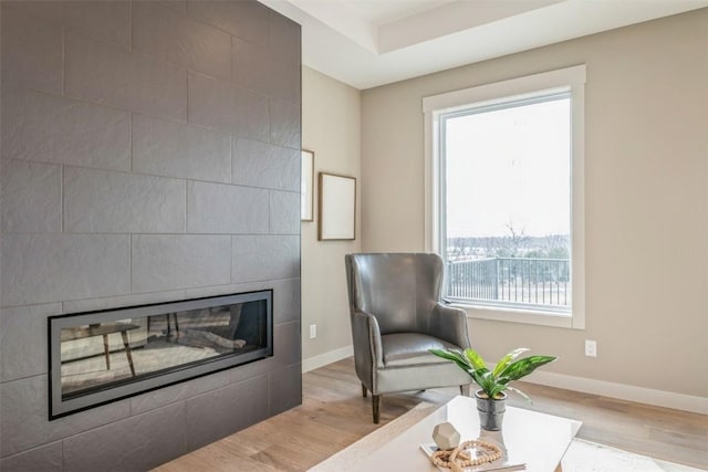 living area with light hardwood / wood-style floors, plenty of natural light, and a tiled fireplace