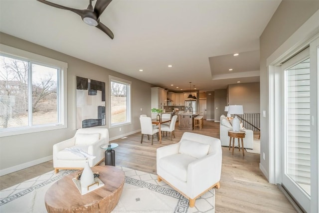 living room featuring ceiling fan, light hardwood / wood-style flooring, and sink