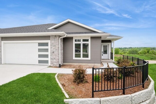 618 J Ave NE, Cedar Rapids, IA 52402 - view of front facade with an attached garage, concrete driveway, roof with shingles, and stone siding