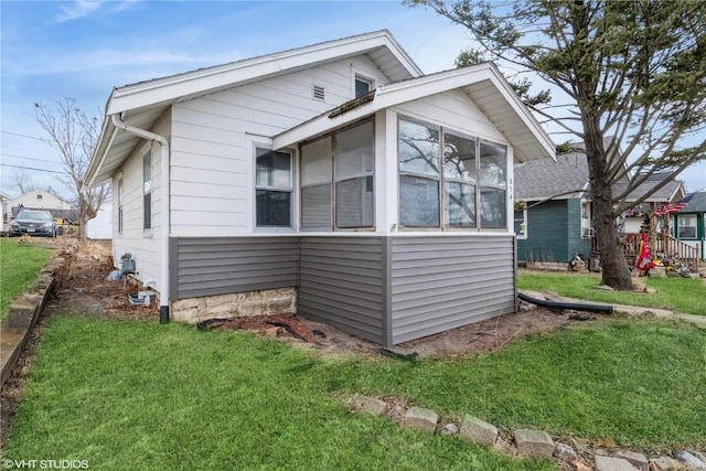 view of side of property with a sunroom and a lawn