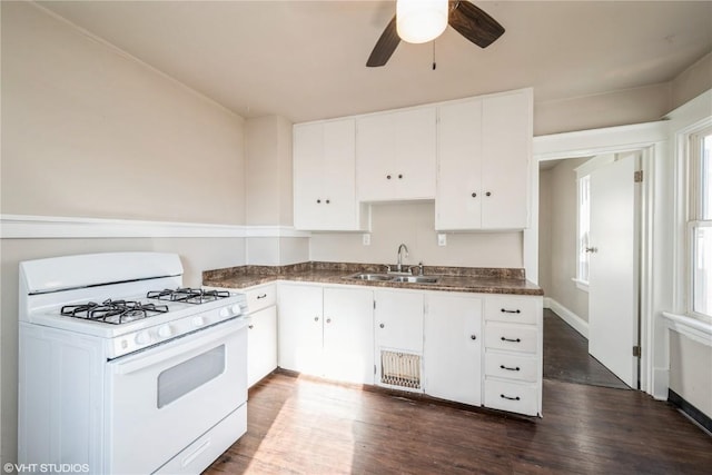 kitchen with gas range gas stove, white cabinetry, ceiling fan, dark hardwood / wood-style floors, and sink