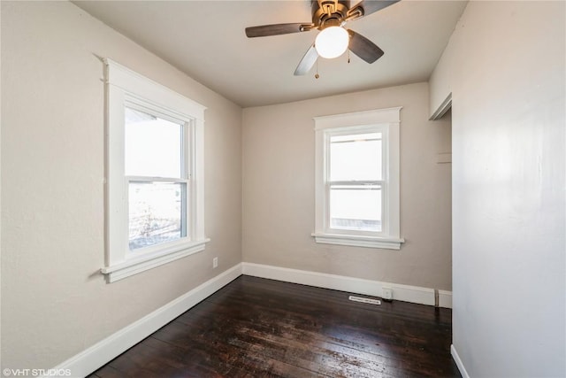 empty room featuring ceiling fan, plenty of natural light, and dark hardwood / wood-style flooring