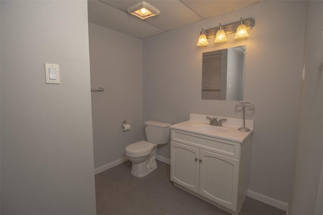 bathroom with toilet, vanity, and a paneled ceiling