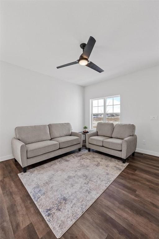 living room with dark wood-type flooring and ceiling fan