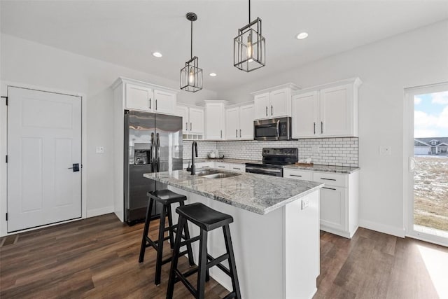 kitchen with stainless steel appliances, white cabinets, light stone counters, and decorative light fixtures