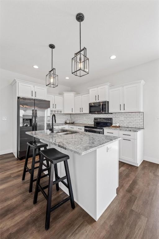 kitchen with sink, white cabinetry, stainless steel appliances, and a kitchen island with sink