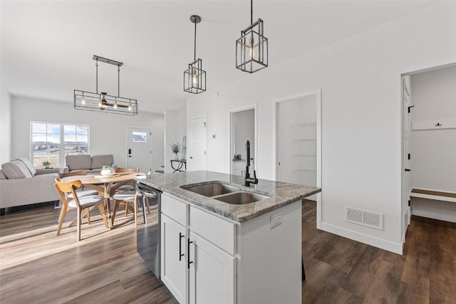 kitchen featuring white cabinetry, a kitchen island with sink, dishwasher, pendant lighting, and sink