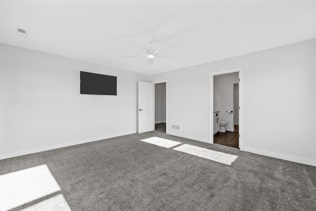 unfurnished bedroom featuring ceiling fan, ensuite bathroom, and dark colored carpet