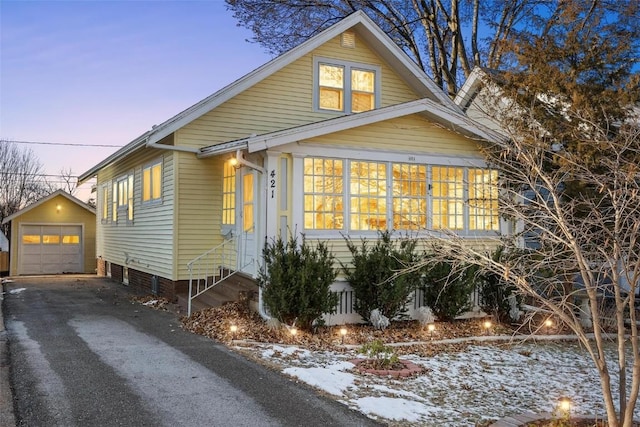 snow covered property featuring an outdoor structure and a garage