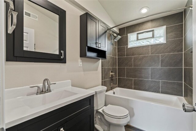 full bathroom with toilet, vanity, lofted ceiling, and tiled shower / bath