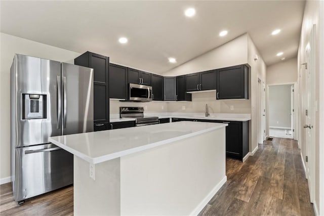 kitchen featuring vaulted ceiling, a center island, sink, stainless steel appliances, and dark hardwood / wood-style flooring