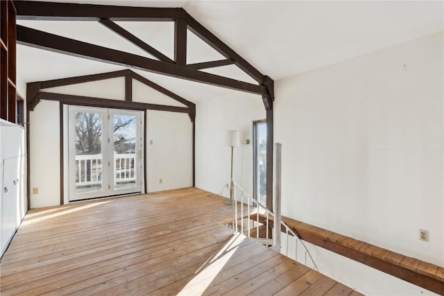 unfurnished living room with light hardwood / wood-style floors, lofted ceiling with beams, and french doors